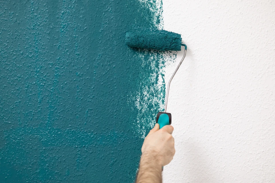 Peintre professionnel appliquant de la peinture rouge sur mur intérieur avec rouleau à peinture